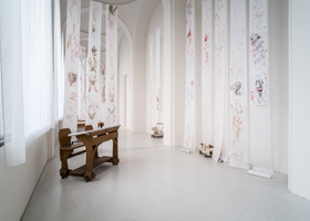 Pélagie Gbaguidi (geb. 1965, Dakar) The Missing Link. Dicolonisation Education by Mrs Smiling Stone (2017) Schulbänke, Fotografien, WERKLISTE Glassinepapierbögen, Zeichnungen mit Farbstift, Mikrofonständer, Erde und Lippenstift auf Papier, Digitalvideos, Musikaufnahme, Handpuppen und Marionetten, diverses Spielzeug Maße variabel Fotografien von Dr. Peter Magubane Leihgaben des Münchner Stadtmuseums, Stadtmuseum Kassel, VS Vereinigte Spezialmöbelfabriken GmbH & Co. KG