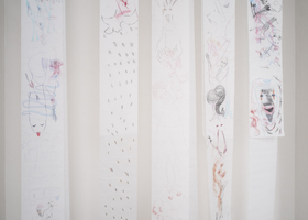 Pélagie Gbaguidi (geb. 1965, Dakar) The Missing Link. Dicolonisation Education by Mrs Smiling Stone (2017) Schulbänke, Fotografien, WERKLISTE Glassinepapierbögen, Zeichnungen mit Farbstift, Mikrofonständer, Erde und Lippenstift auf Papier, Digitalvideos, Musikaufnahme, Handpuppen und Marionetten, diverses Spielzeug Maße variabel Fotografien von Dr. Peter Magubane Leihgaben des Münchner Stadtmuseums, Stadtmuseum Kassel, VS Vereinigte Spezialmöbelfabriken GmbH & Co. KG